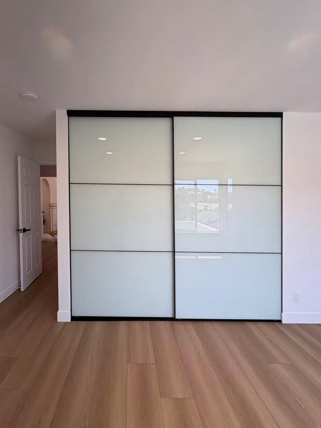 White glass bypass sliding closet doors installed, black frame