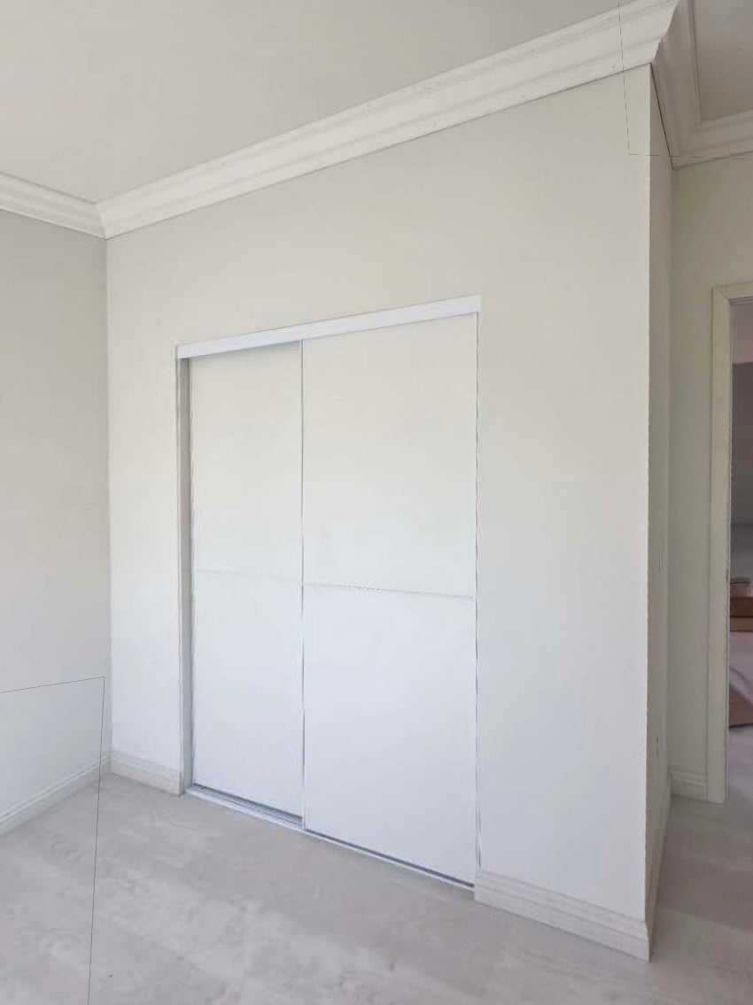 White panel sliding closet doors installed in a bedroom